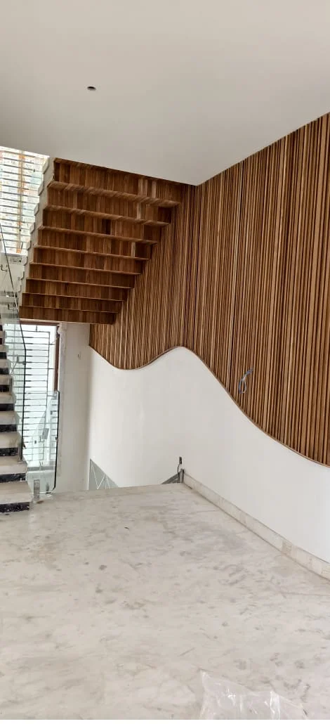 Architectural fluted timber wall paneling following an organic wave profile alongside cantilevered wooden steps