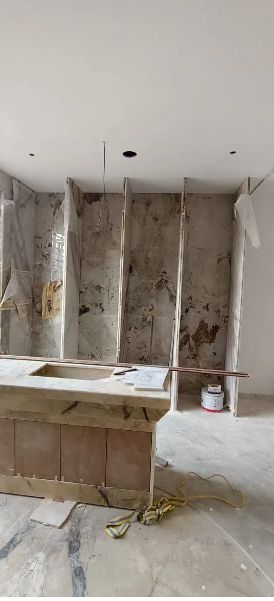 Under-construction view of backlit onyx bar counter showing stone cladding and plywood internal framework