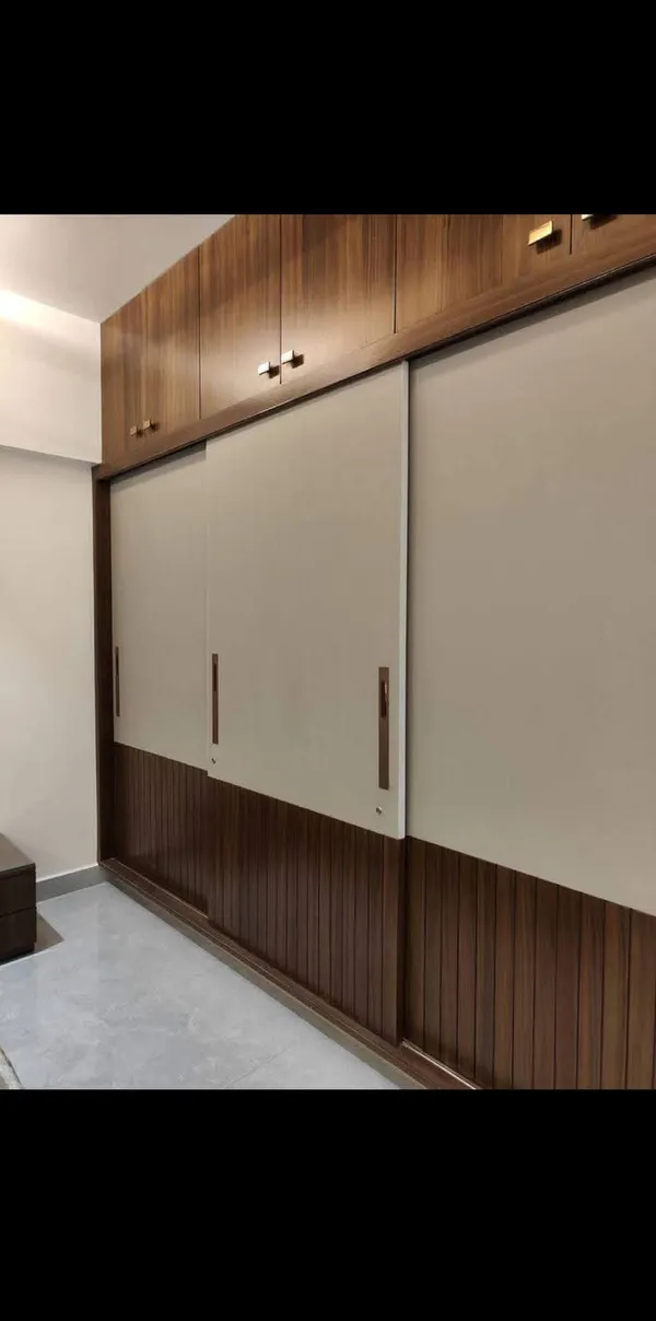 Full-height modern sliding door wardrobe with walnut fluted lower panels and matte beige upper shutters
