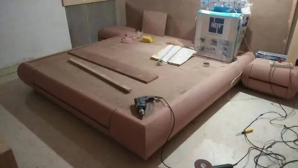 On-site carpentry assembly of custom curved low-platform bed with rounded bedside drawer consoles