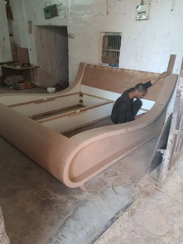 Workshop fabrication of an organic curved wave sleigh bed structure crafted with bent plywood joinery
