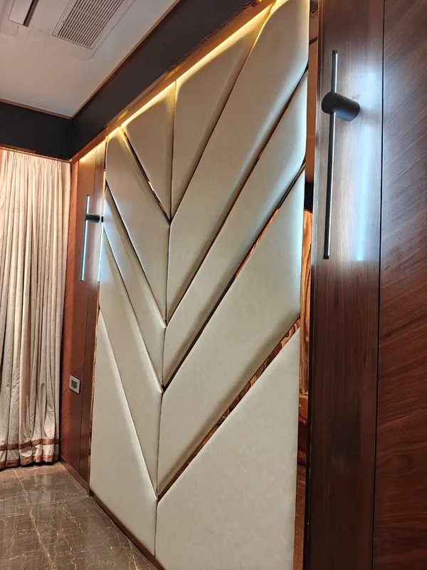 Full-height geometric chevron upholstered acoustic wall paneling with rose-gold metallic T-profile inlays and cove lighting