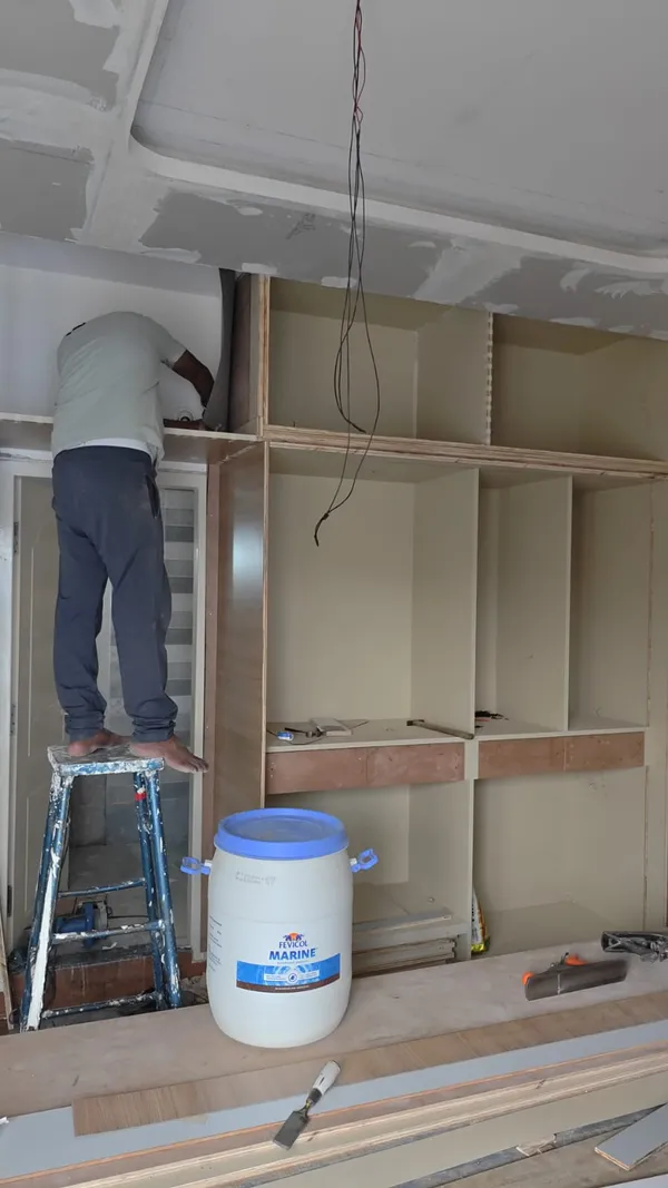 Carpenter fitting concealed soft-close drawer runners inside custom bedside furniture