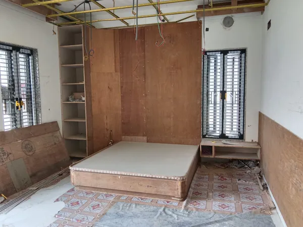 Wide construction view of bedroom showing platform bed base, bookshelf framework, and ceiling channels