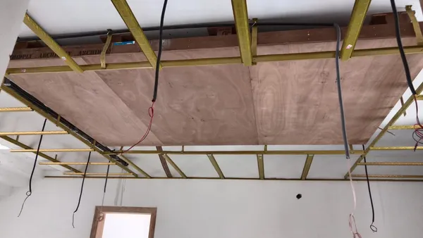 Mid-stage execution showing arched TV wall, desk workstation, and gold ceiling channels