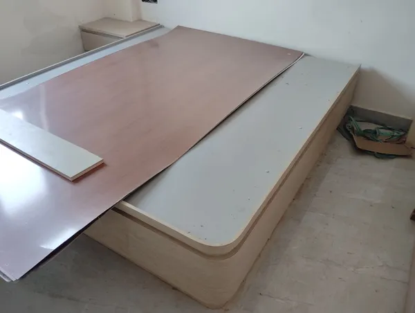 Custom platform bed with curved plywood corners during laminate sheet pressing and edge-banding